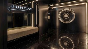 A modern elevator with a 'RUNWAY' sign, a bench, and a circular ventilation feature.