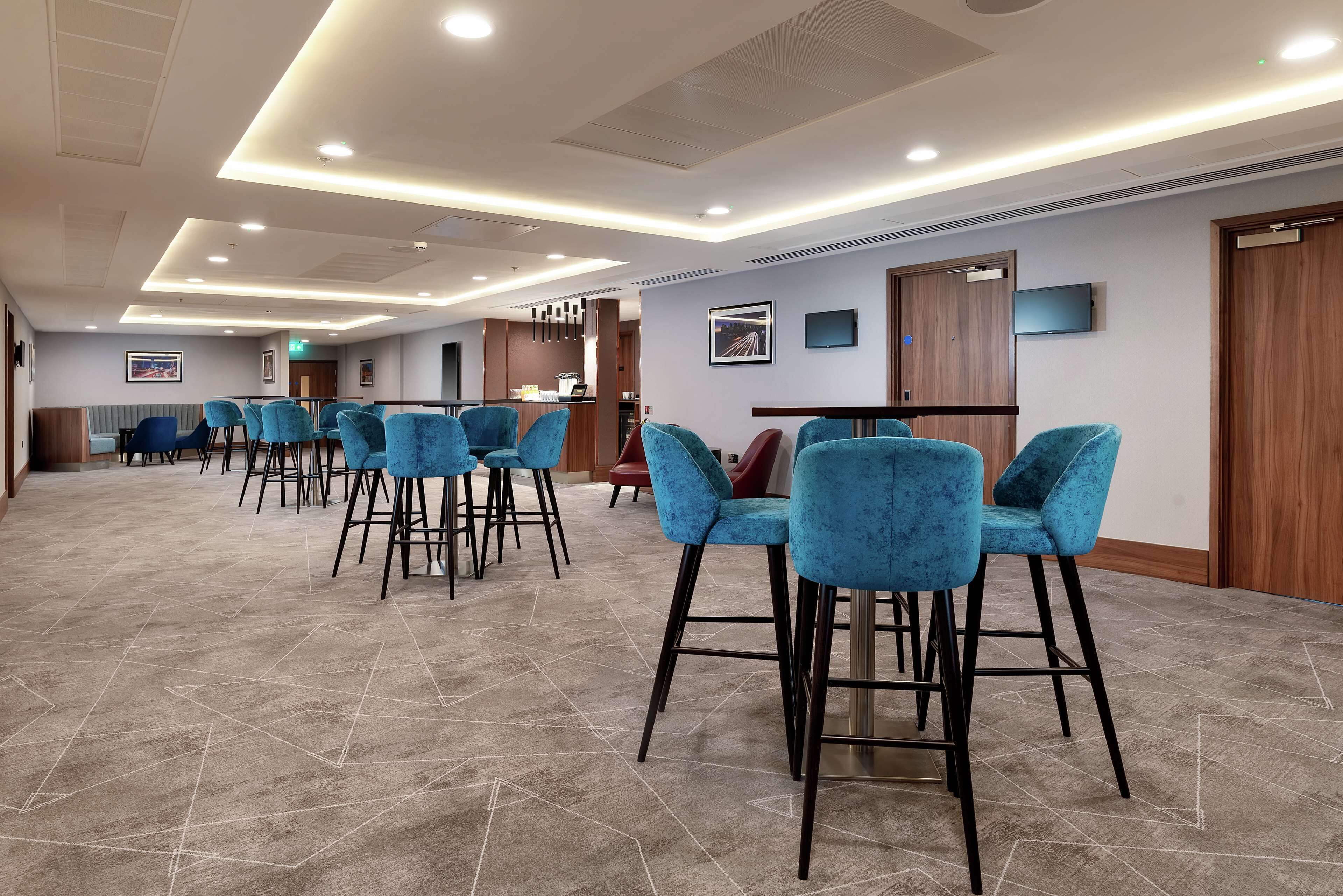 A hotel lobby with a modern design, featuring a reception area, seating area with chairs, and a patterned carpet.