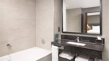 Un baño moderno con bañera, un espejo grande y encimera de mármol.