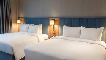 Habitación de hotel con dos camas, cabecera de madera, lámpara y teléfono en la mesita de noche.