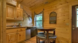 A wooden interior with a kitchen area, a dining table with bar stools, and a sign reading "Tom Knight's Sportsbar".
