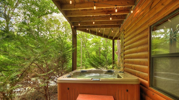 A wooden cabin with a hot tub and a picnic table.