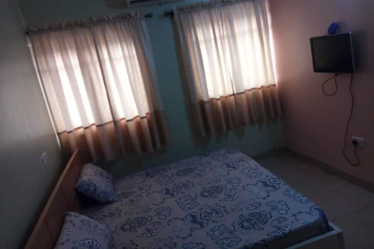 Un dormitorio con cama, cortinas, aire acondicionado y televisor.
