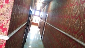 Un pasillo con paredes decoradas y suelo a cuadros, que conduce a una habitación luminosa al final.