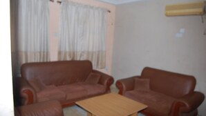 Una habitación con dos sofás de cuero marrón, una mesa de centro de madera y cortinas color crema.