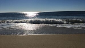 Una playa con cielos despejados y luz del sol reflejada en el agua.