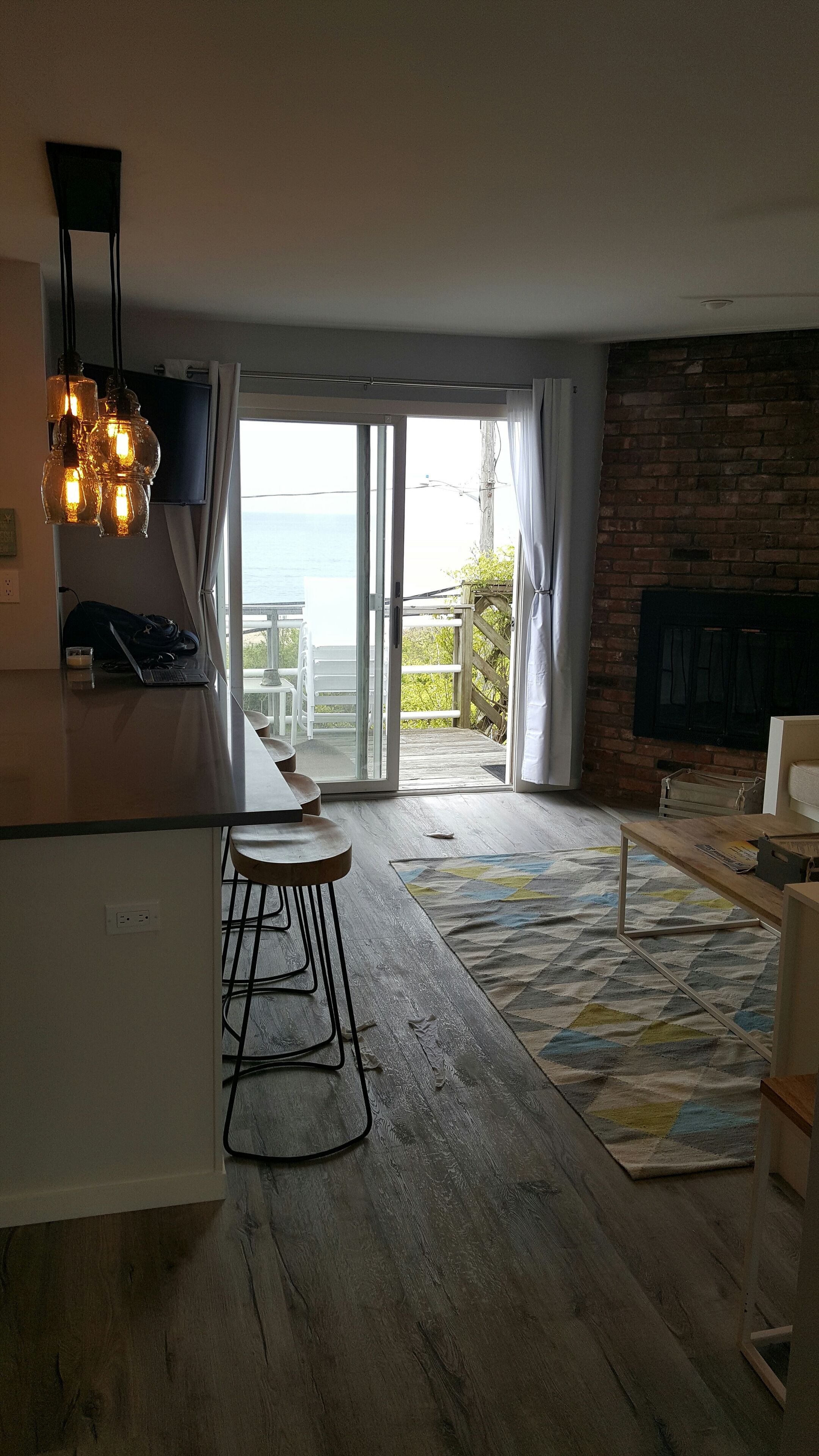 Una cocina moderna con barra, un amplio ventanal corredera que da a un balcón y una pared de ladrillo.
