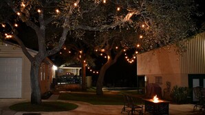 Un patio con luces de cuerda, una chimenea y mobiliario para exteriores.