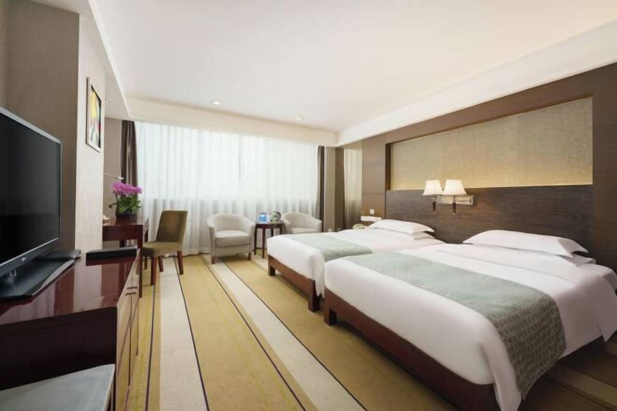 Une chambre d’hôtel avec deux lits, une télévision, un bureau et une chaise.