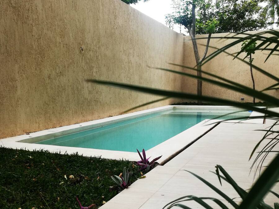 A swimming pool with a tiled deck and a low wall.