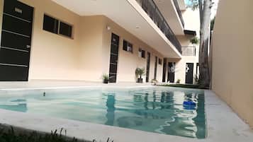 Una piscina al aire libre, sillones reclinables de piscina