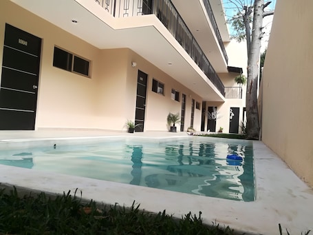 Una piscina al aire libre, sillones reclinables de piscina