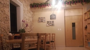 A dining area with wooden chairs and a table, a stone wall, and a door with a sign above it. - Hotel Virreyes (Mérida)