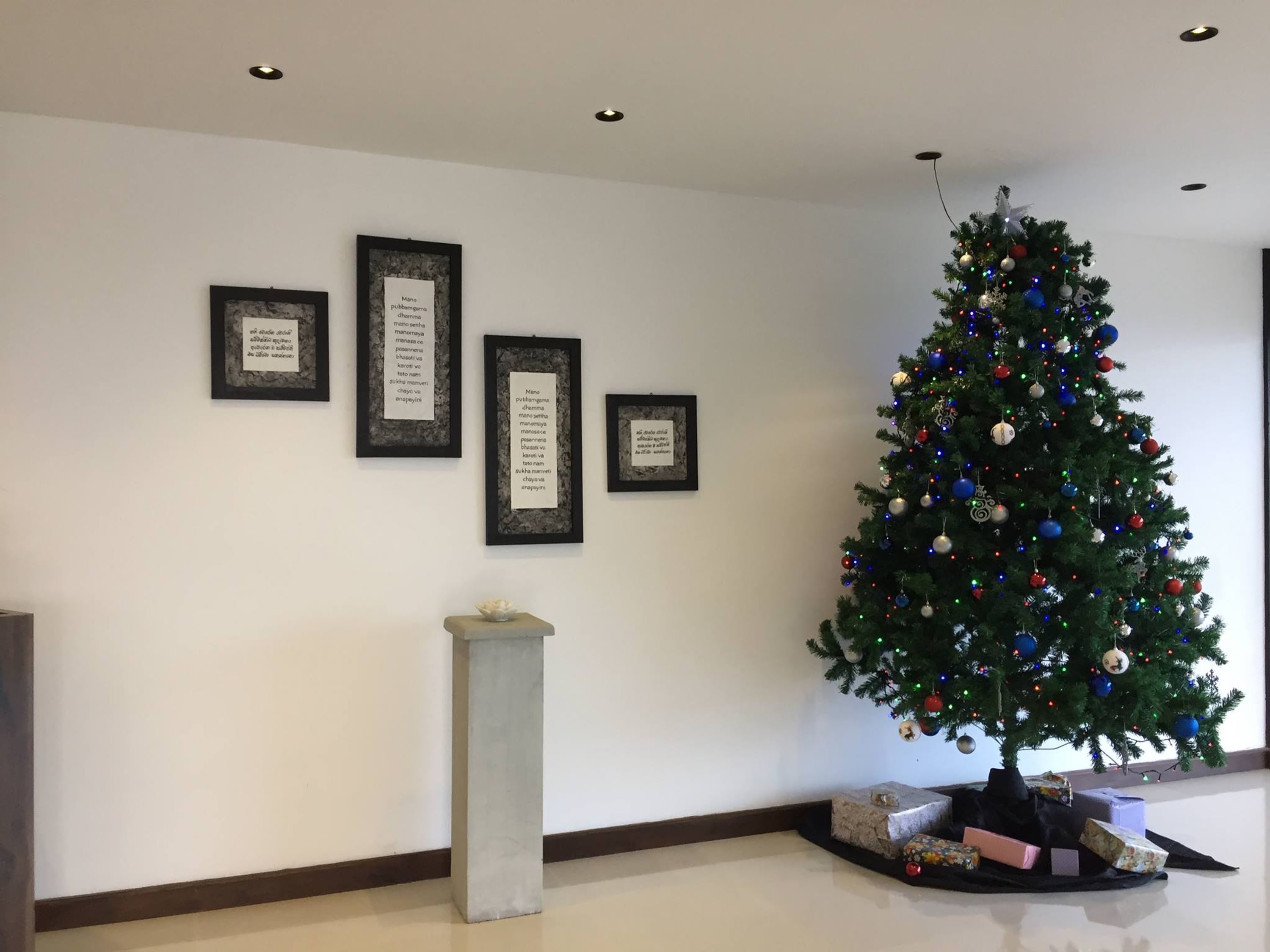 A decorated Christmas tree with lights and ornaments, surrounded by wrapped gifts on the floor.
