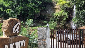 A natural landscape with a waterfall, a gate, and a large rock with the letters "AKWAY" on it. - Akway Resort (Beragala)