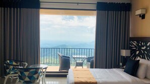 A hotel room with a bed, a table with chairs, a view of the mountains, and a balcony. - Akway Resort (Beragala)
