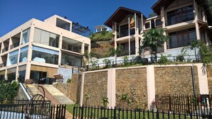 A multi-story hotel with a stone retaining wall, a staircase, and a flag. - Akway Resort (Beragala)