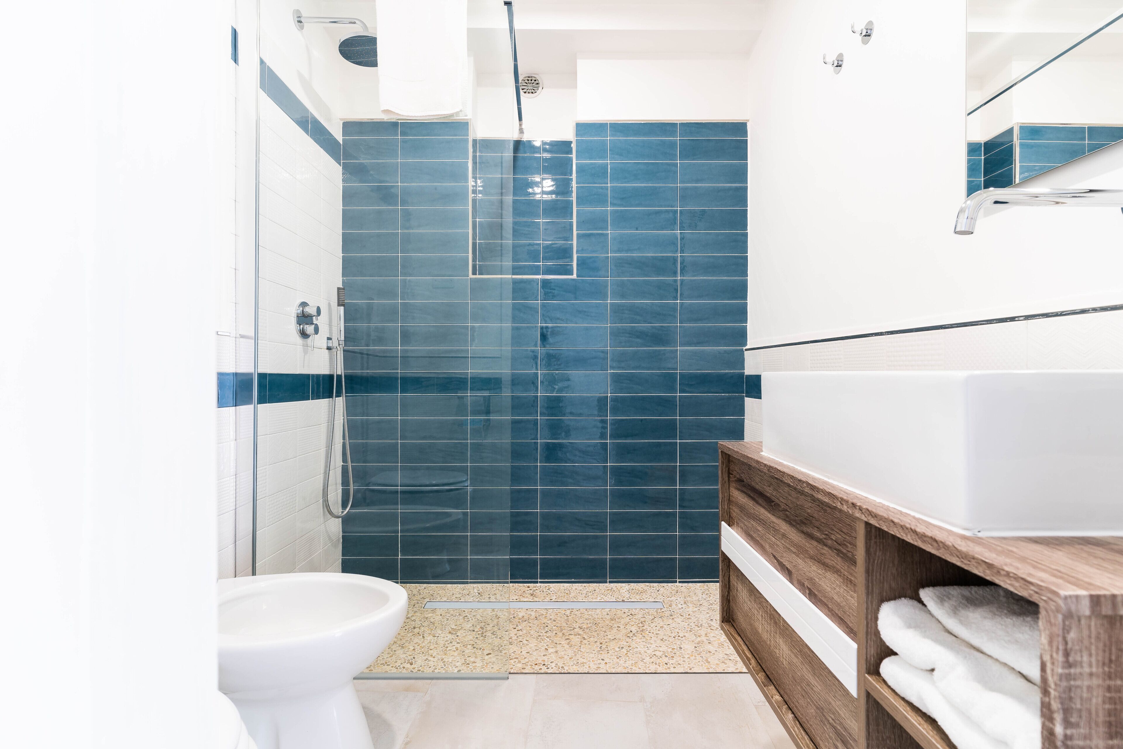A modern bathroom with a shower, toilet, and a wooden vanity with towels.