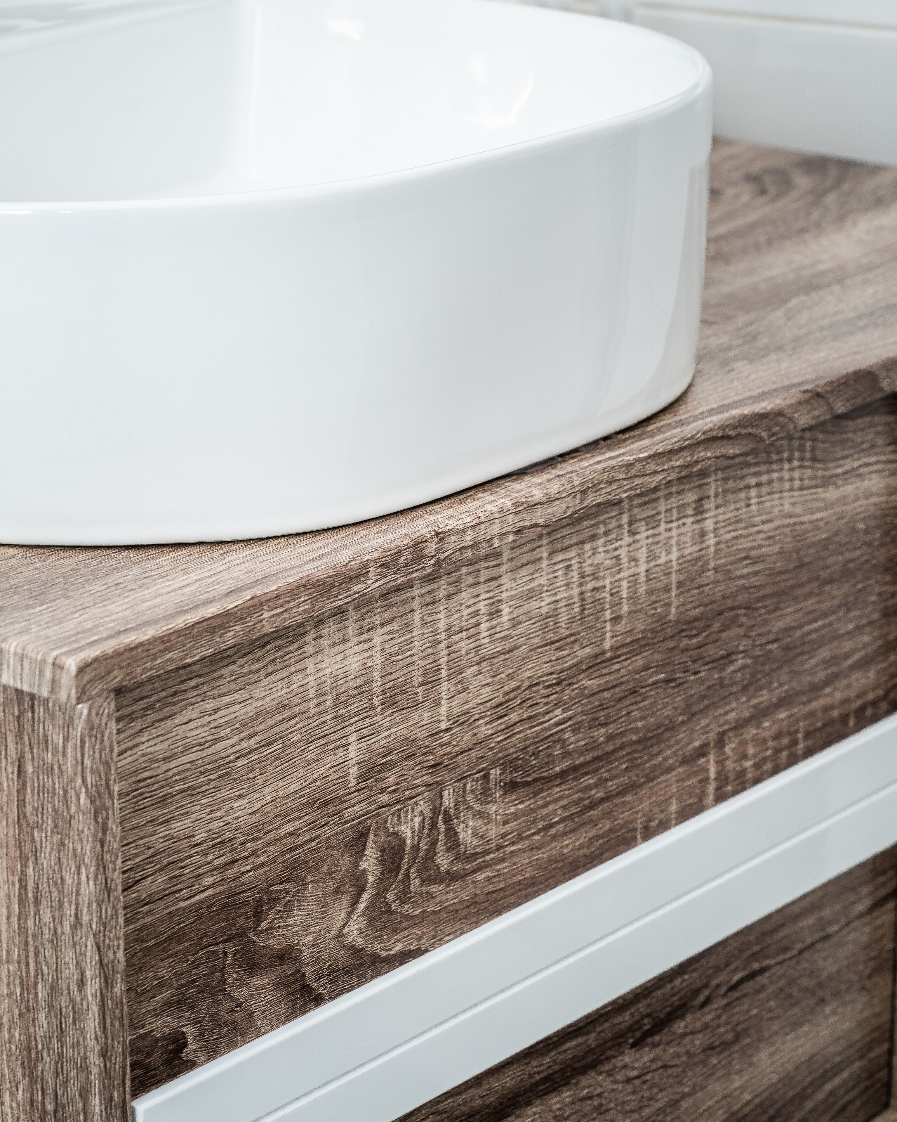 Un lavabo blanco sobre una encimera de madera con un cajón debajo.