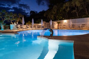 A swimming pool with a waterfall feature, lounge chairs, and umbrellas. - Relais Freedom Club (Massa Lubrense)