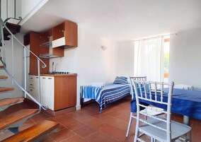 Una habitación compacta con cocina, una cama con colcha a rayas y una silla.