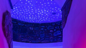 A stone-walled hot tub with blue and red lighting, a bucket, and glasses on the floor. - Relais Freedom Club (Massa Lubrense)