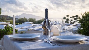 A table set for a meal with a bottle, glasses, and cutlery, overlooking a mountainous landscape. - Relais Freedom Club (Massa Lubrense)