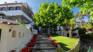 A stone pathway leading to a building with a white facade, red flowers, and a green lawn. - Relais Freedom Club (Massa Lubrense)
