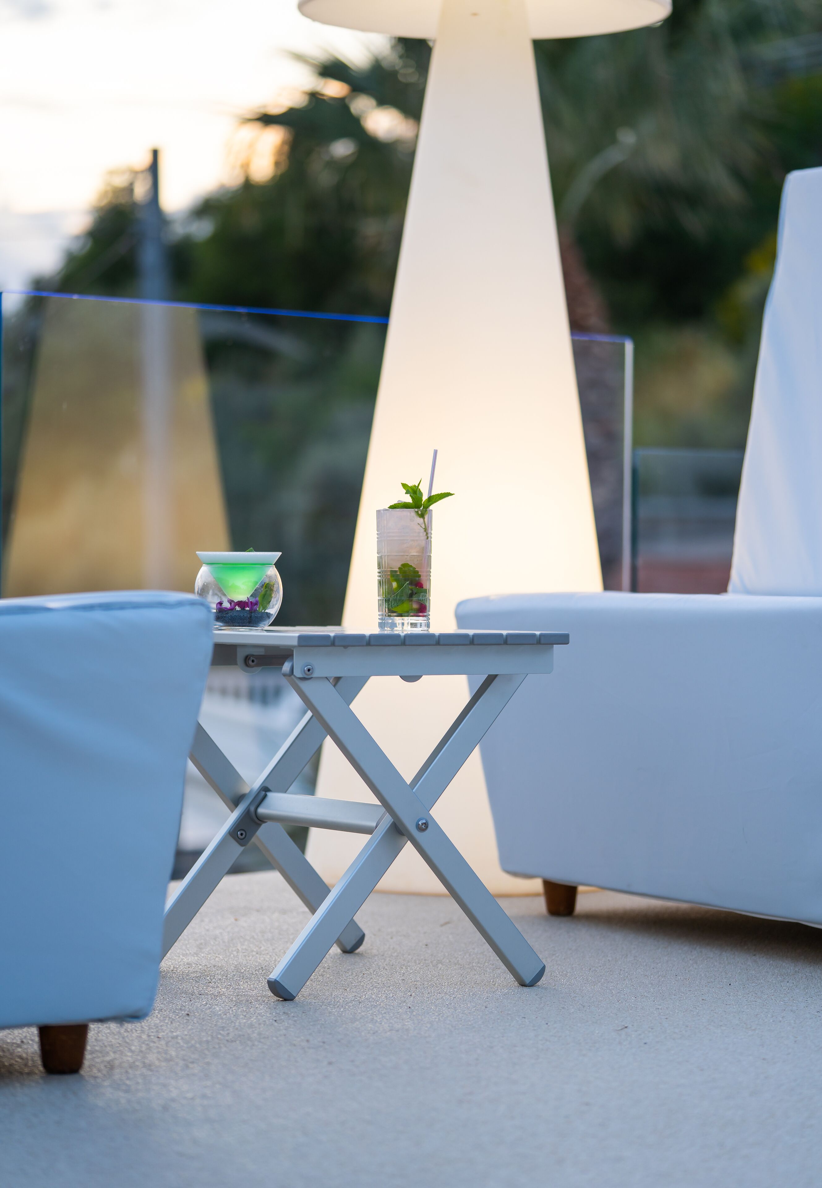 A small outdoor seating area with a table, a chair, and a lamp.