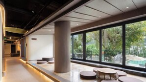 A modern indoor area with a long corridor, large windows, and seating areas.