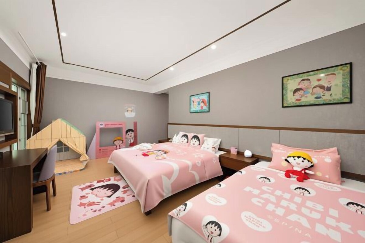A bedroom with two beds, a desk, a chair, and a small play area.