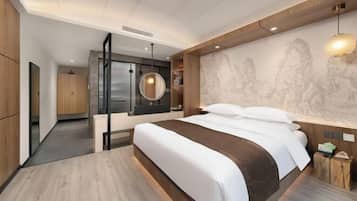 A modern hotel room with a large bed, a wooden headboard, a marble wall with a relief sculpture, and a round pendant light.