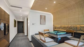 A modern room with a pool table, seating, and a stone accent wall.