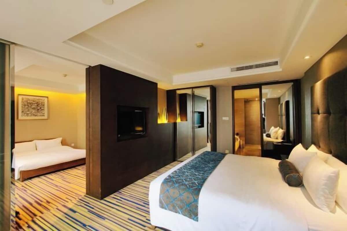 Une chambre d’hôtel avec un grand lit, une télévision, un miroir et une moquette à motifs.