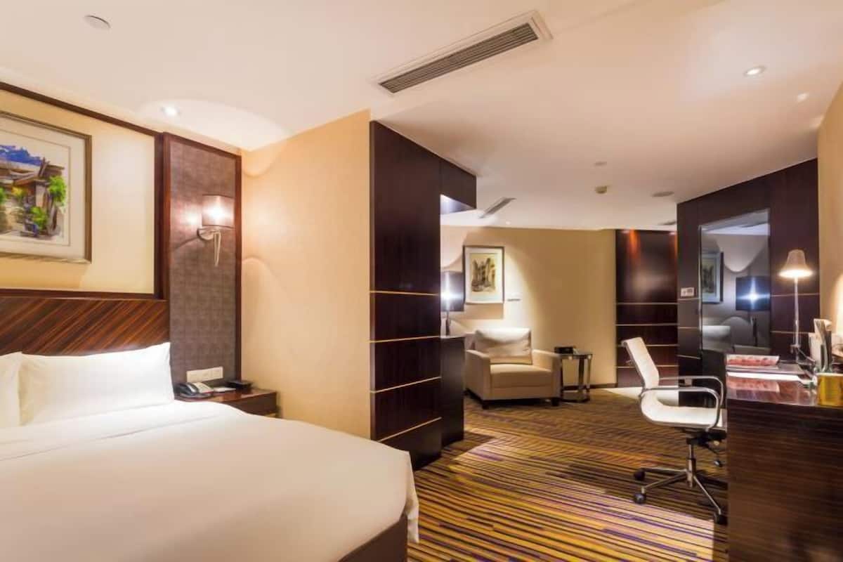 Une chambre d’hôtel avec un lit, un bureau, une chaise et une petite table.