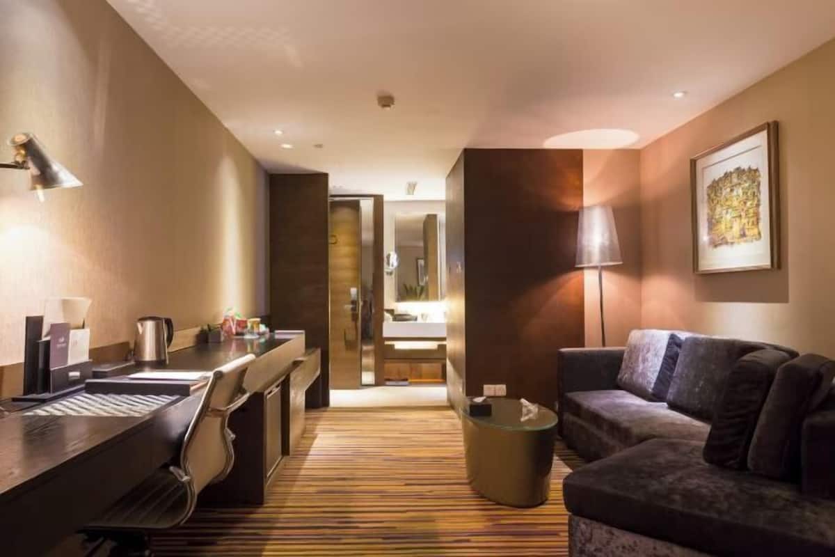 Une chambre d’hôtel équipée d’un bureau, d’un canapé, d’une lampe et d’un tableau encadré au mur.