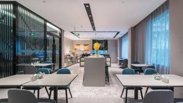 A modern hotel lobby with a central island, seating arrangements, and a view of the kitchen area.