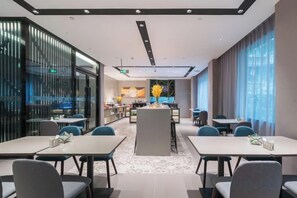 A modern hotel lobby with a central island, seating arrangements, and a view of the kitchen area.