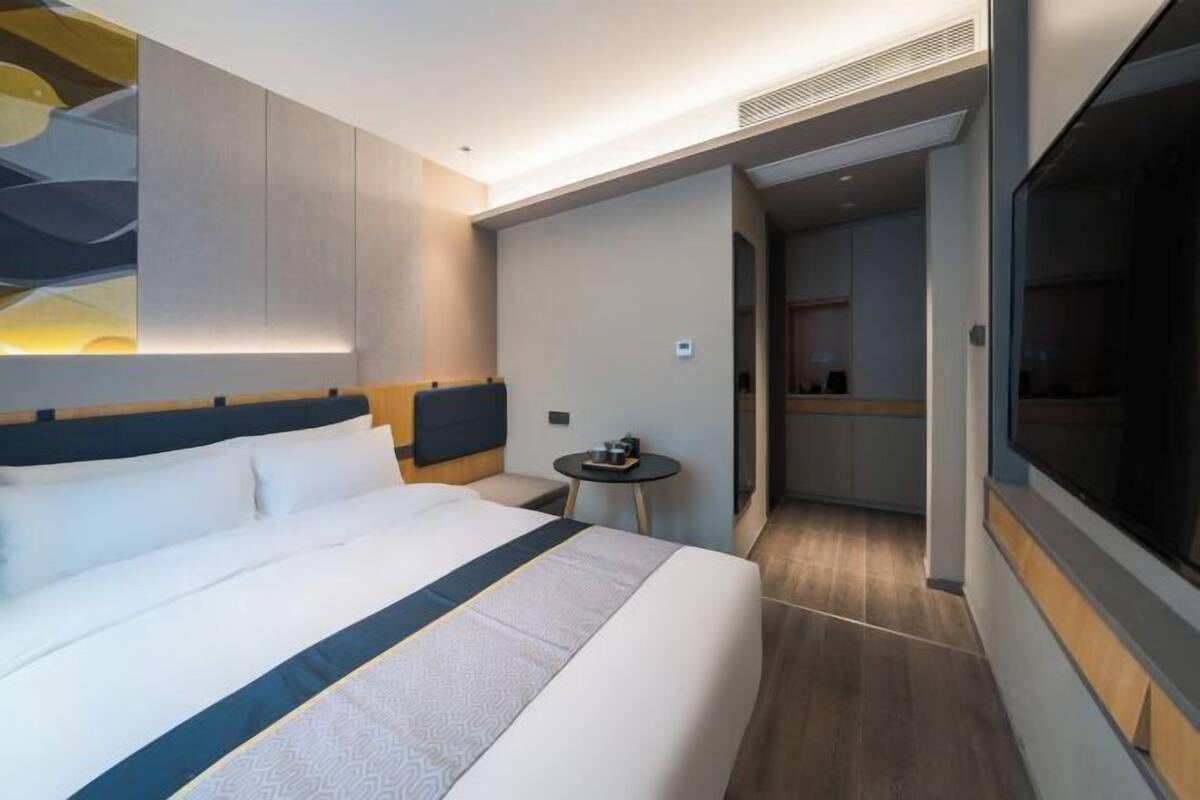 A modern hotel room with a large bed, a small table, and a TV.