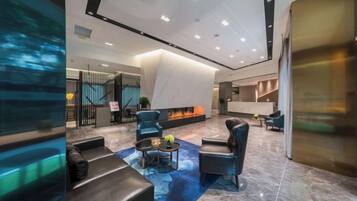 A modern lobby with seating areas, a fireplace, and a reception desk.
