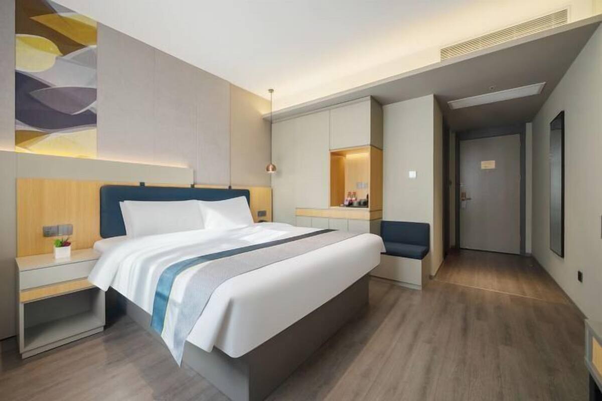 A modern hotel room with a large bed, bedside tables, a desk, and a seating area.