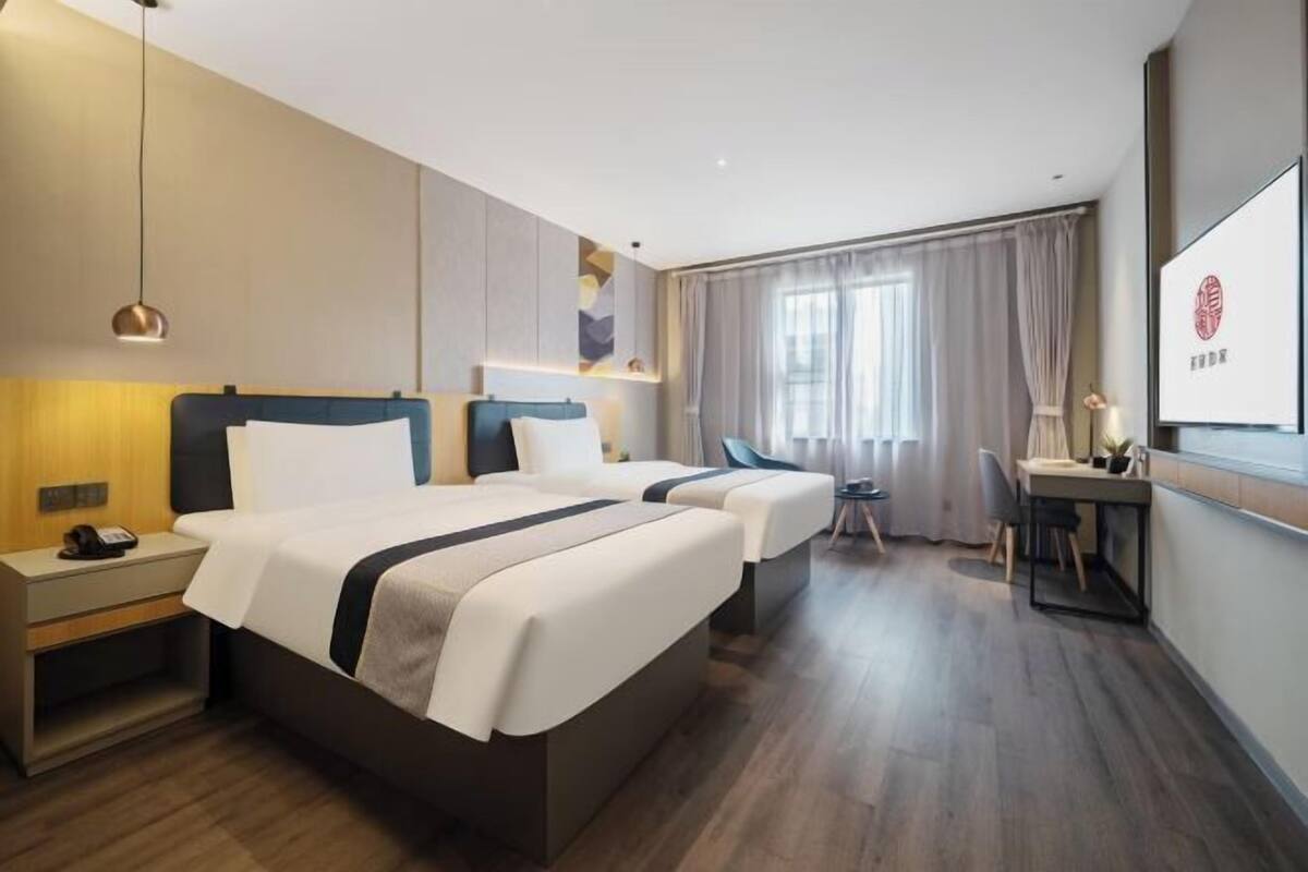 A hotel room with two beds, a desk, and a chair.
