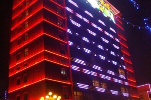 Un edificio de varios pisos con ventanas iluminadas y una entrada destacada.