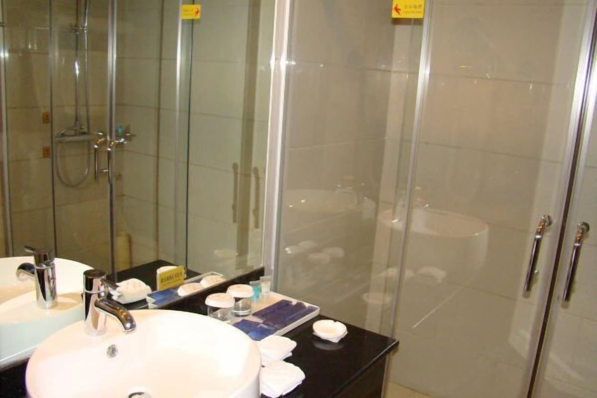 A modern bathroom with a glass-enclosed shower, a white sink with a chrome faucet, and a mirror above the sink.