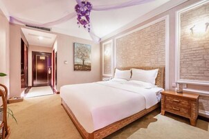 Un dormitorio con una cama grande, una mesita de noche de madera, una pared de acento de piedra y una puerta que da a otra habitación.