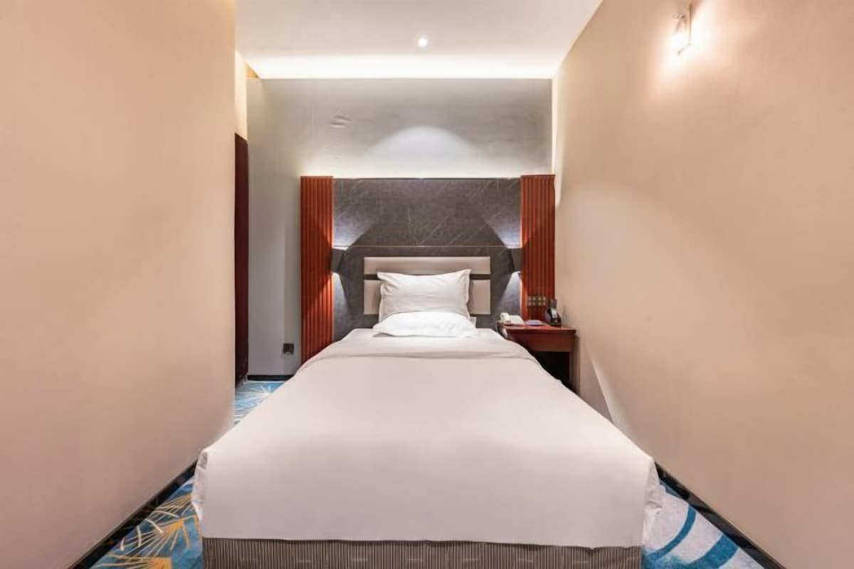A hotel room with a bed, a nightstand, and a headboard.