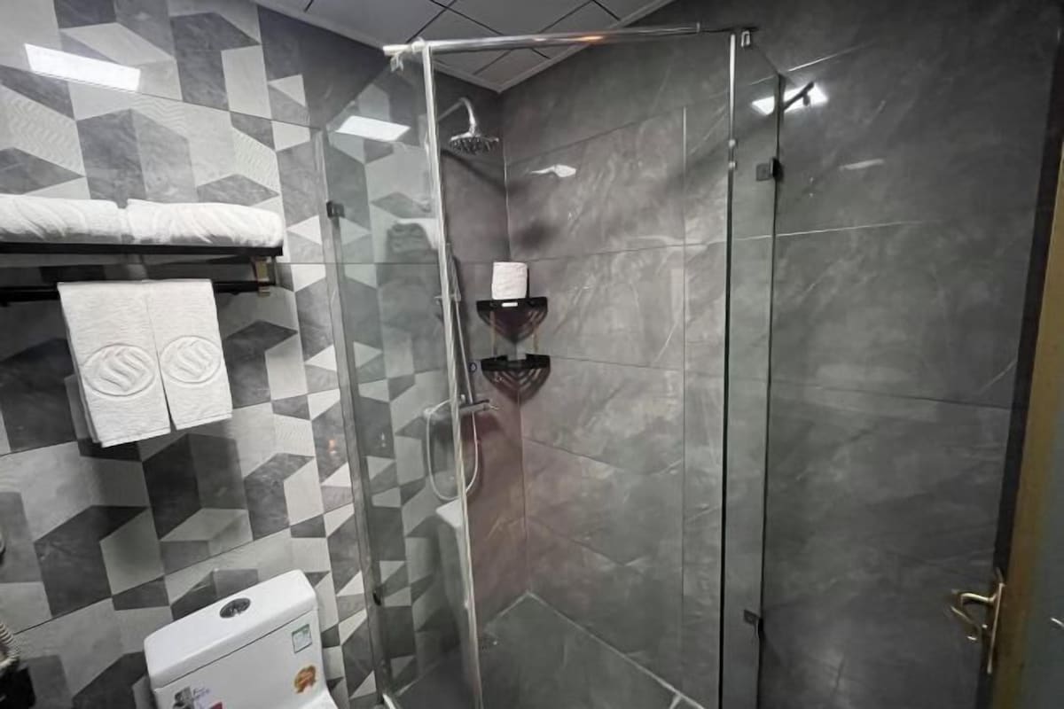 A modern bathroom with a shower, tiled walls, and a toilet.
