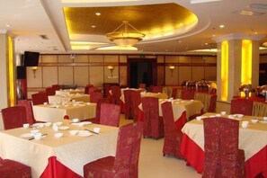 A banquet hall with round tables, red chairs, and a gold ceiling. - Zhulinshan Hotel (Yangcheng)