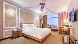 Une chambre d’hôtel dotée d’un grand lit, d’un coin salon avec un canapé et d’un téléviseur fixé au mur.