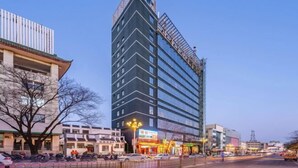 Un hôtel moderne, de grande hauteur, qui se distingue par son architecture aux lignes originales, ses nombreux étages et son entrée imposante avec une façade en verre.